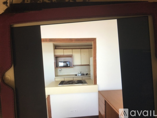 A kitchen with white countertops and wooden cabinets is visible through a window.