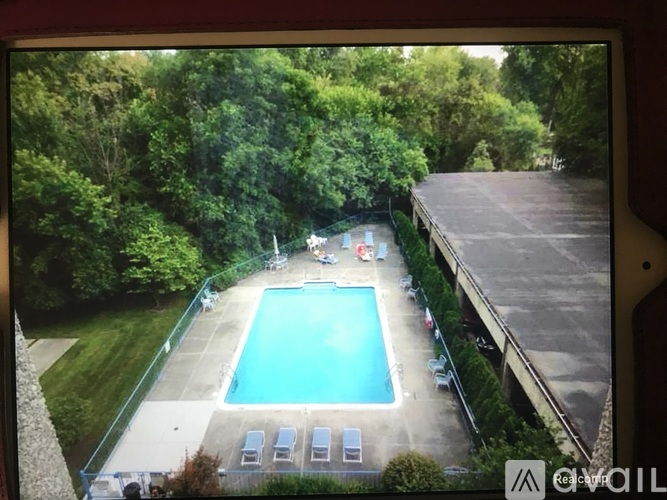 A pool surrounded by trees and a building.