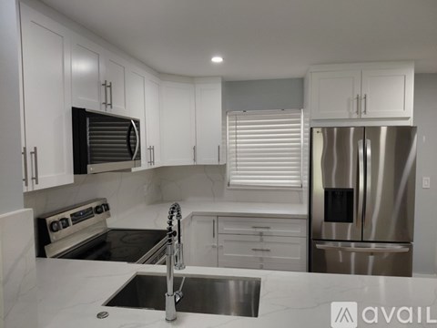 A modern kitchen with white cabinets and stainless steel appliances.