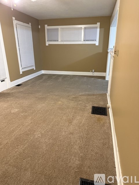 A room with a carpeted floor and a window with blinds.