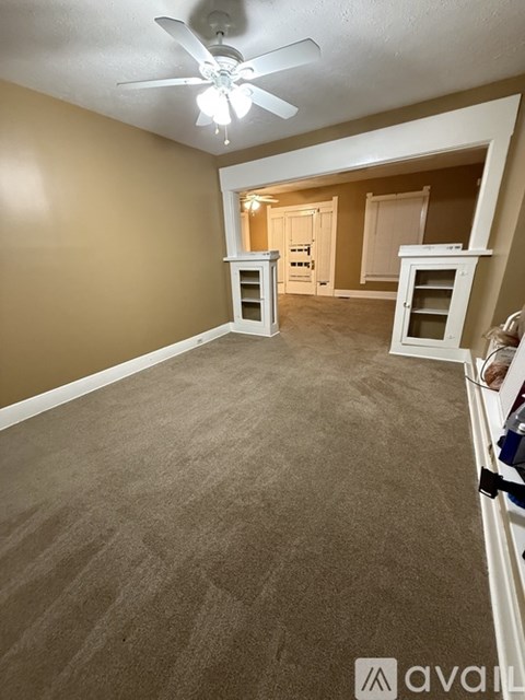 A room with a ceiling fan and carpeted floor.