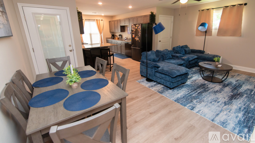 A dining room with a table set for six and a couch with blue cushions.