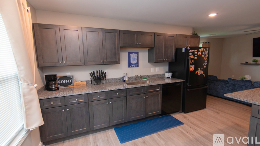 A kitchen with dark wood cabinets and a black fridge.