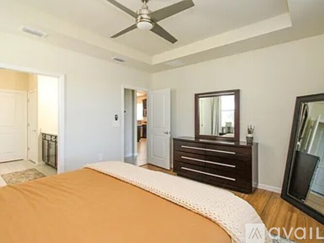 A bedroom with a bed, dresser, mirror, and a ceiling fan.