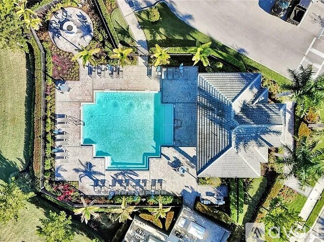 A large swimming pool surrounded by a concrete patio and a stone wall.