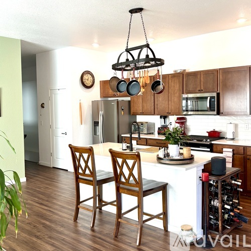 A kitchen with a white island and wooden chairs.