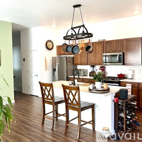 A kitchen with a white island and wooden chairs.