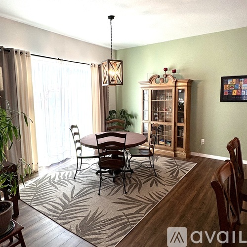A dining room with a round table surrounded by chairs and a cabinet with glass doors.