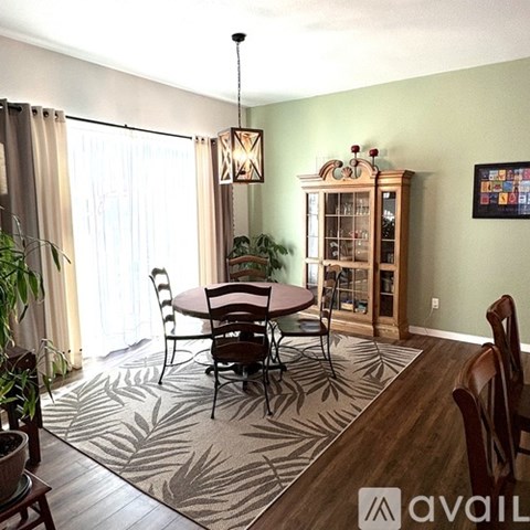 A dining room with a round table surrounded by chairs and a cabinet with glass doors.