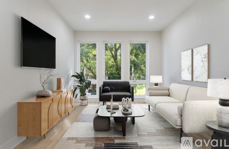 A modern living room with a large window and a flat screen TV mounted on the wall.