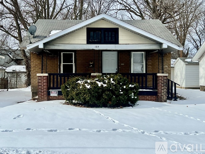 A house with a snow-covered ground in front of it.