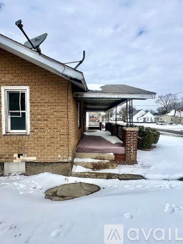 A house with a satellite dish on the roof and snow on the ground.