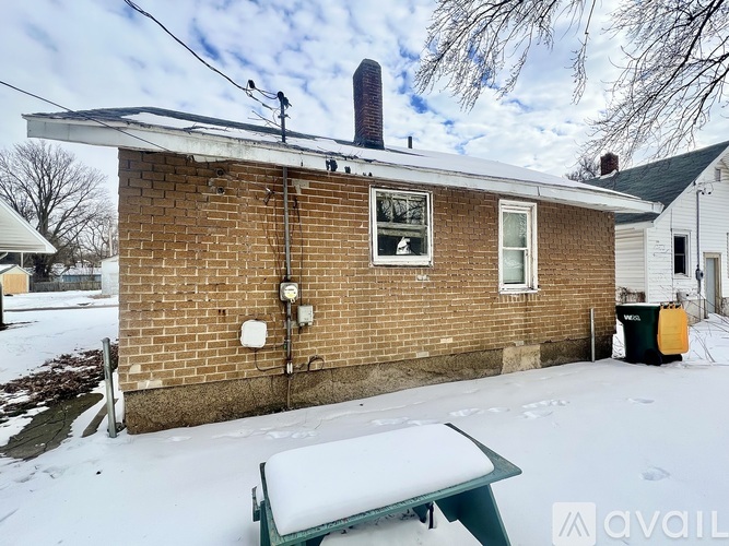 A house with a snow-covered roof and a green bench in front.