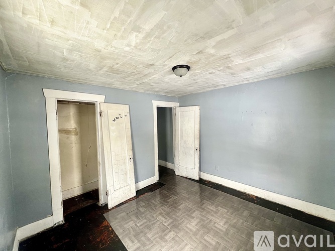 A room with a chevron patterned floor and two open doors.