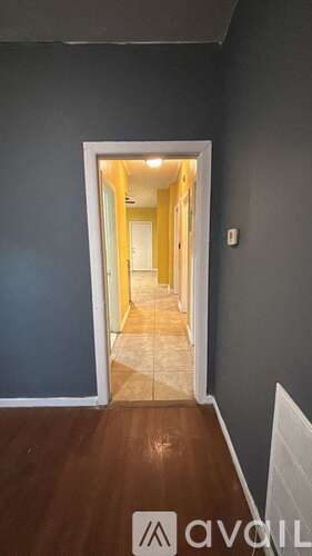 A hallway with a wooden floor and a white door.