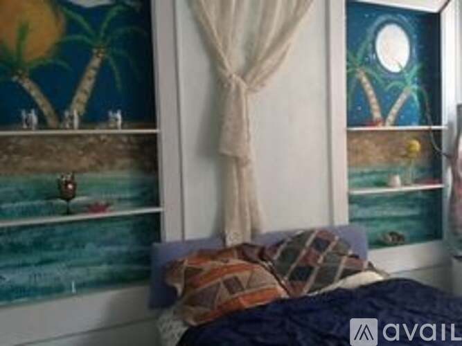 A bedroom with a bed, a window with a curtain, and a painting on the wall.