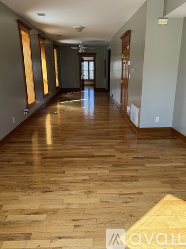 A long hallway with wooden floors and a fan.