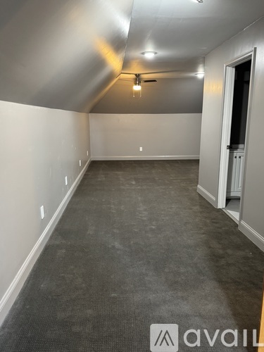 A spacious room with a carpeted floor and a ceiling fan.