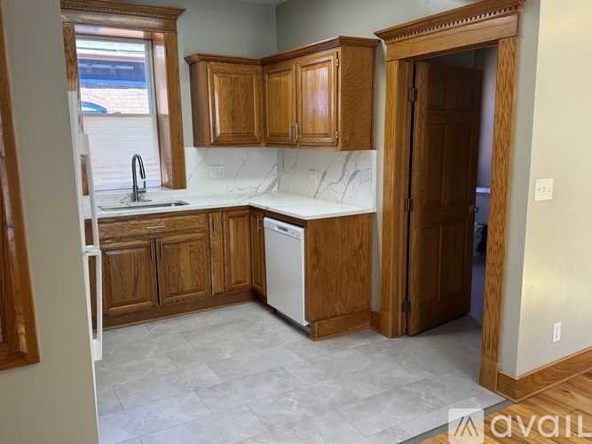 A kitchen with wooden cabinets and a white dishwasher.