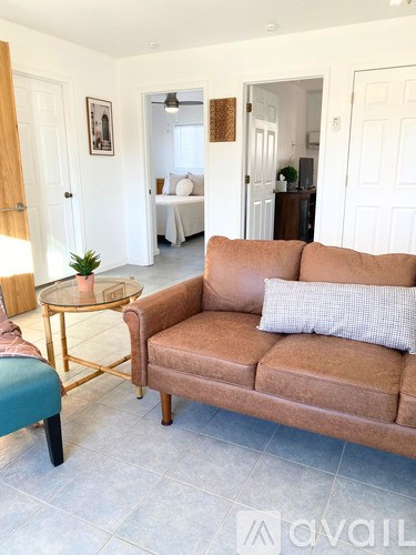 A living room with a brown couch and a glass table.