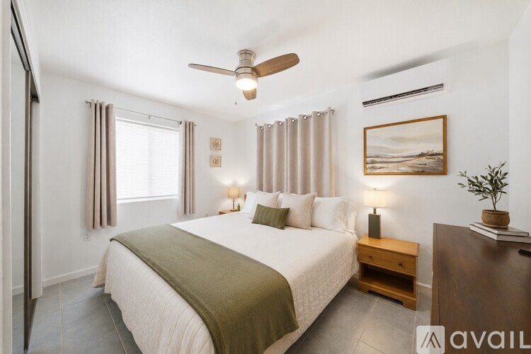 A well-lit bedroom with a large bed and a ceiling fan.