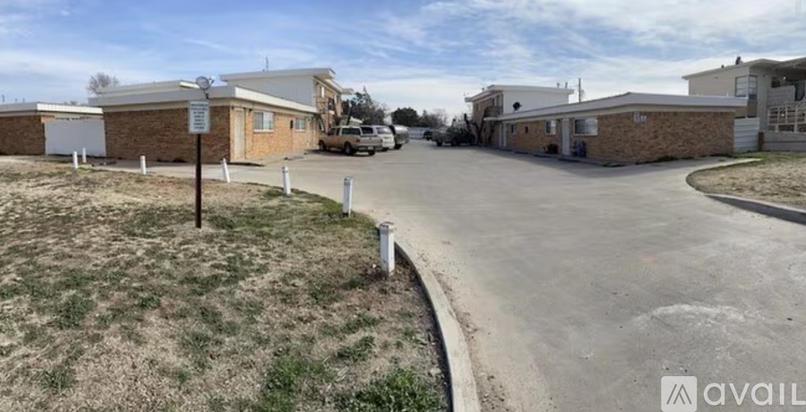 A parking lot with a building and a sign in the background.
