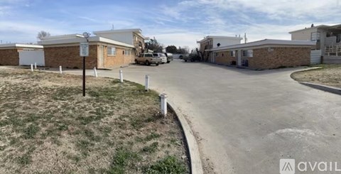 A parking lot with a building and a sign in the background.