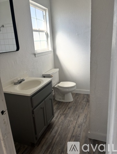 A bathroom with a toilet, sink, and mirror.