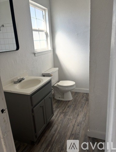 A bathroom with a toilet, sink, and mirror.