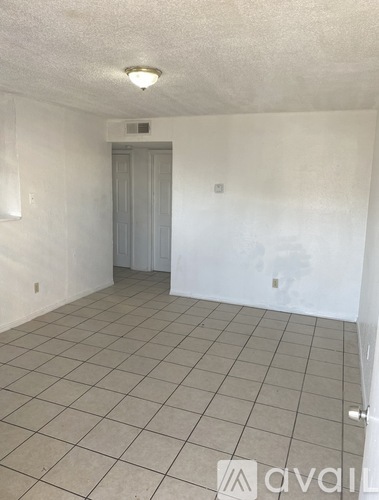 A room with a tiled floor and a door in the background.