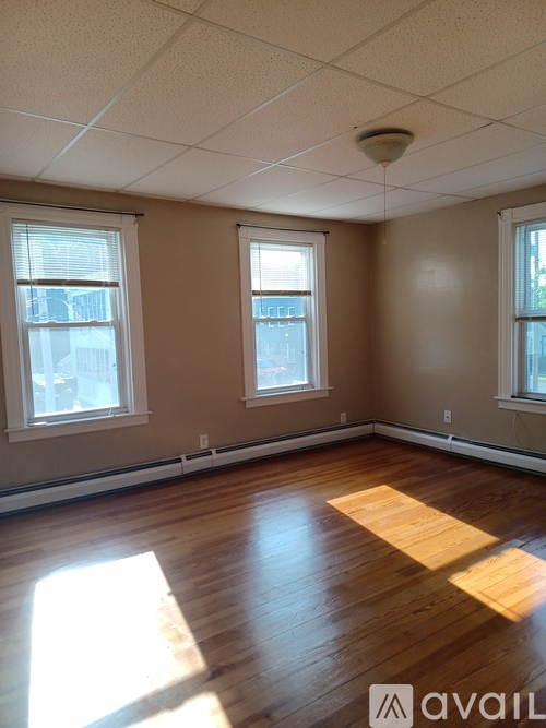 A room with wooden floors and three windows.