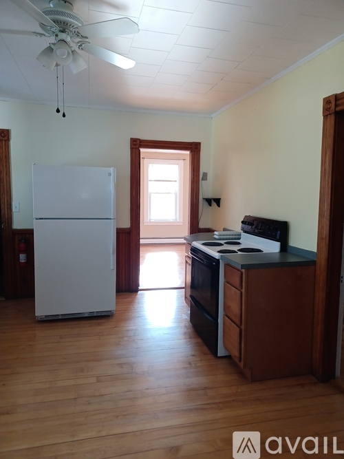 A kitchen with a white fridge and wooden floors.
