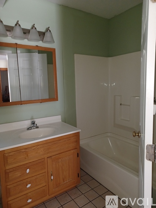A bathroom with a sink, mirror, and bathtub.