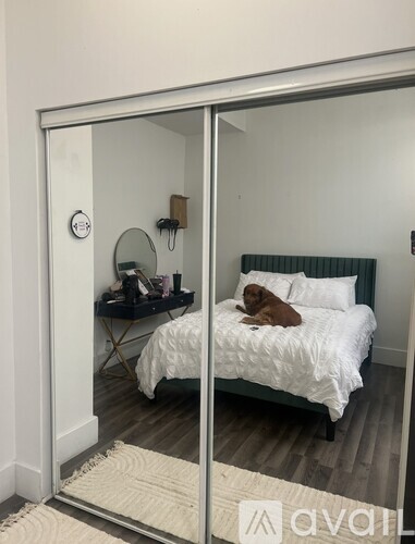 A bedroom with a bed, nightstand, and mirror.