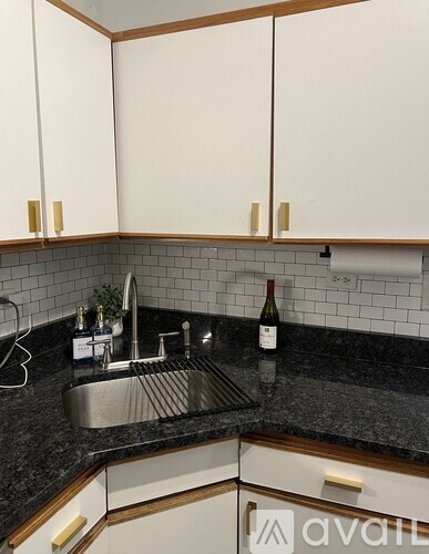 A kitchen with a sink and a bottle of wine on the counter.