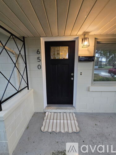 A black door with a glass window and a number 650 on the wall.