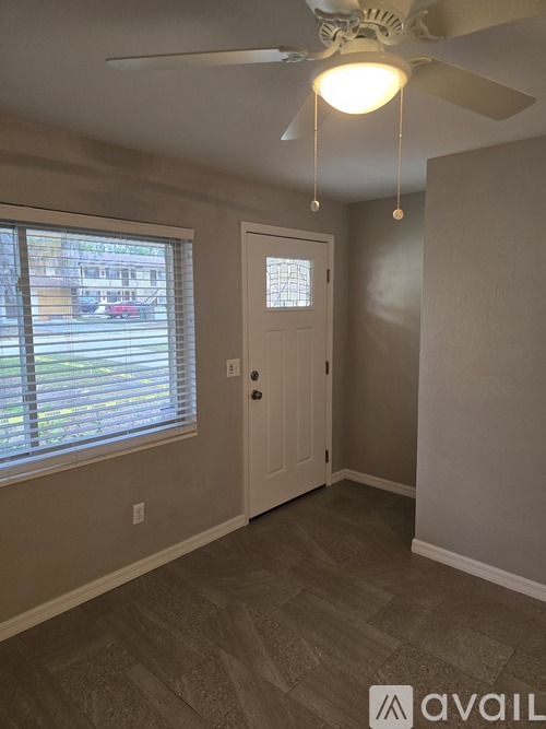 A room with a ceiling fan and a door.