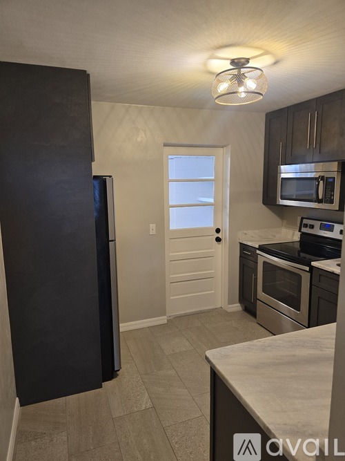 A kitchen with a black refrigerator and stainless steel appliances.