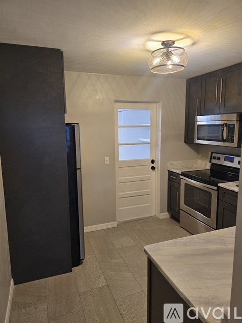 A kitchen with a black refrigerator and stainless steel appliances.