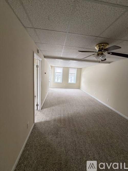 A room with a carpeted floor and a ceiling fan.