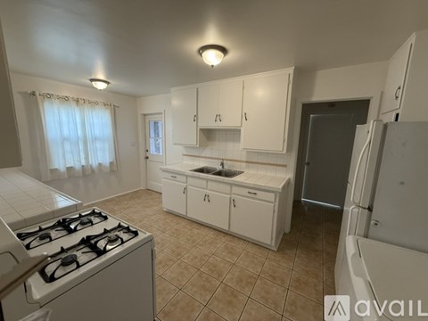 A kitchen with white cabinets and a tiled floor.
