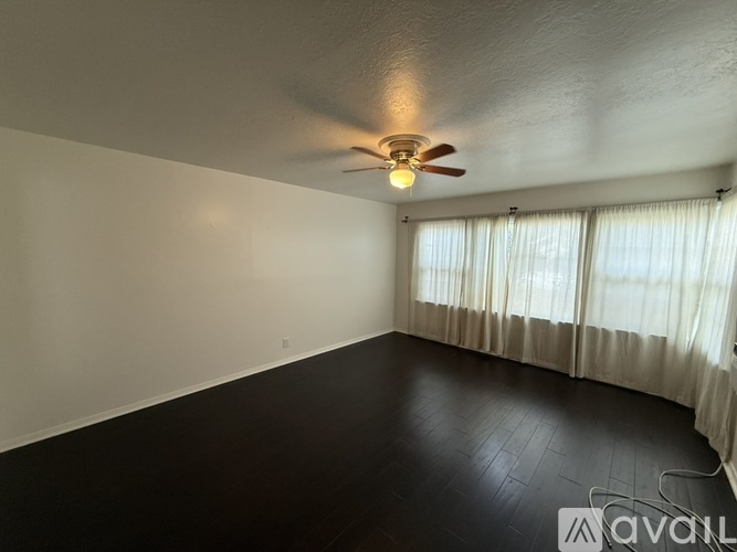A room with a ceiling fan and a window with curtains.