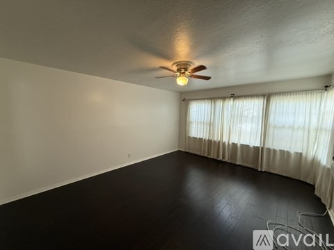 A room with a ceiling fan and a window with curtains.