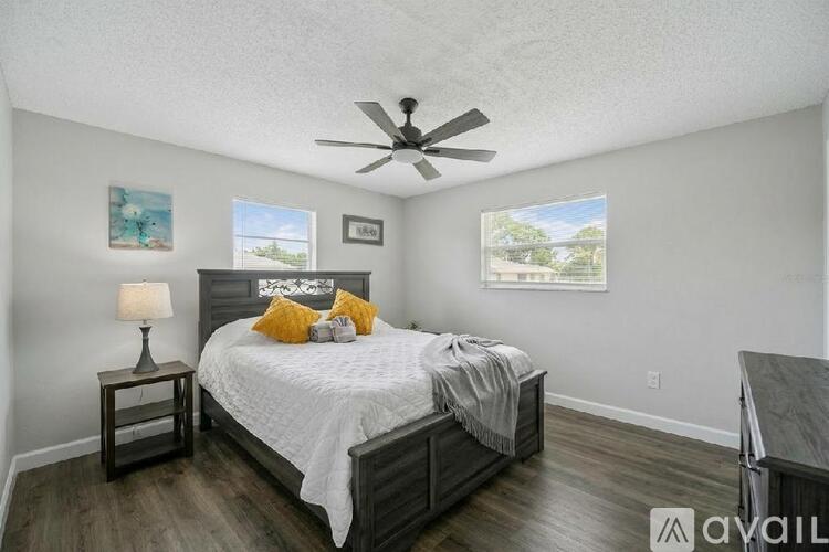 A bedroom with a bed, nightstand, and a fan.