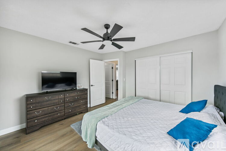 A bedroom with a bed, dresser, and television.