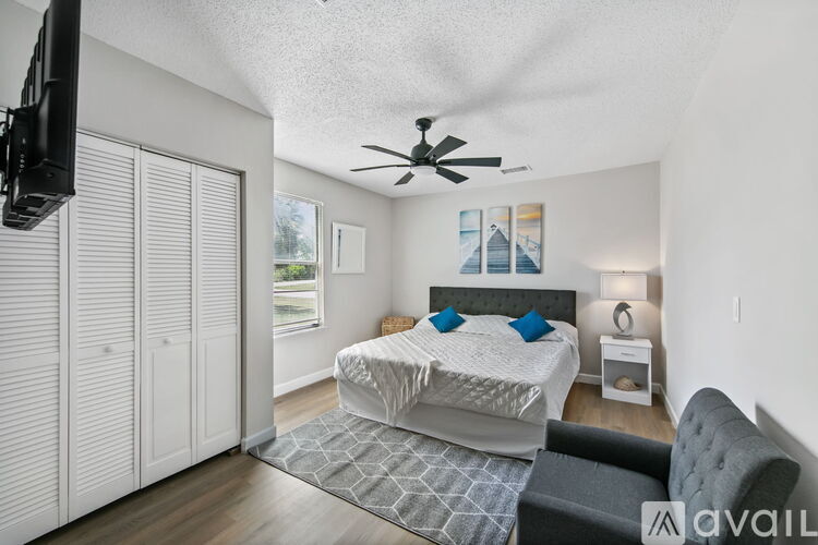 A bedroom with a bed, a chair, and a ceiling fan.