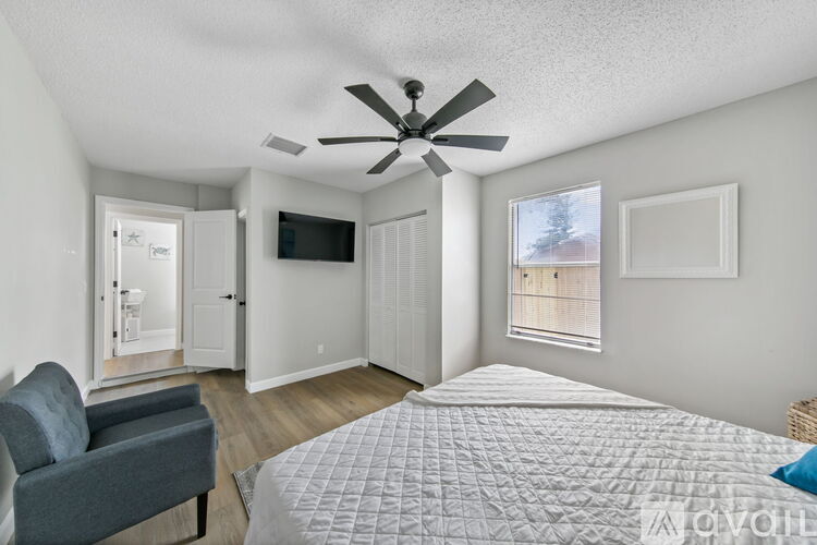 A bedroom with a bed, chair, and a ceiling fan.