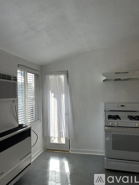 A kitchen with a stove, oven, and a window with curtains.