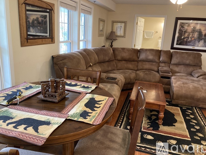 A living room with a brown couch and a coffee table with animal prints.