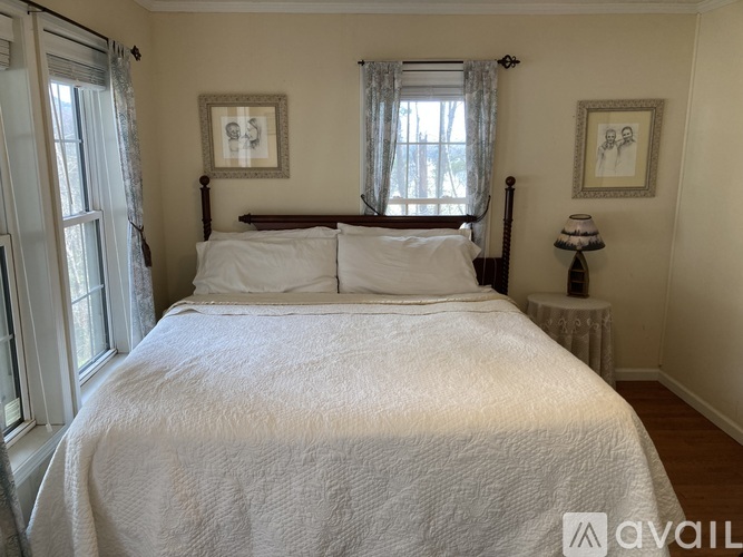 A bedroom with a large bed and two pictures on the wall.